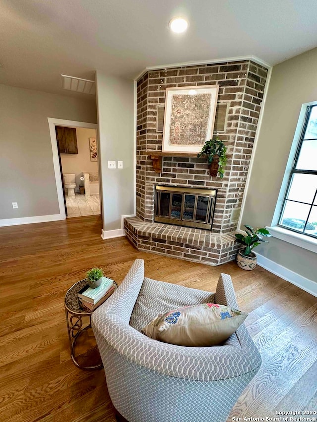 living room featuring brick wall, a brick fireplace, and hardwood / wood-style floors