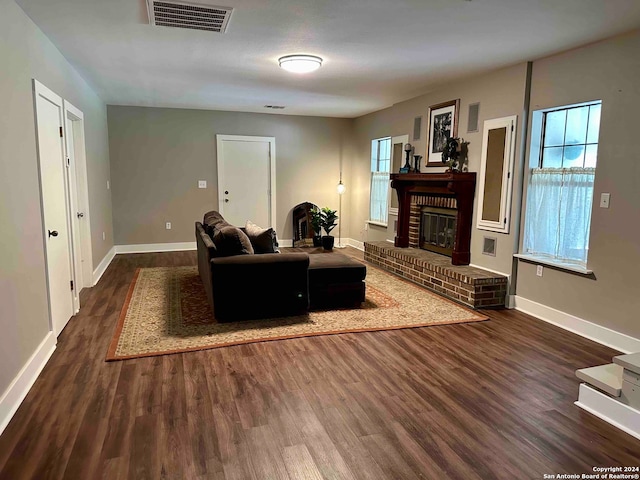 living room with dark hardwood / wood-style flooring and a brick fireplace