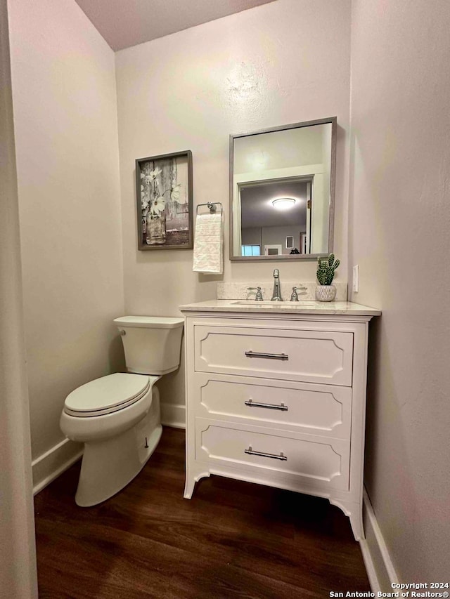 bathroom featuring wood-type flooring, toilet, and vanity