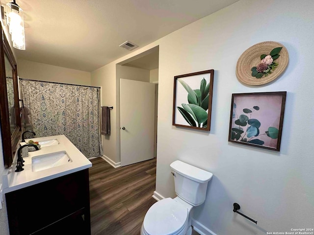 bathroom with hardwood / wood-style flooring, dual vanity, and toilet