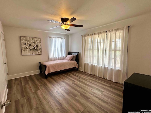 bedroom with multiple windows, hardwood / wood-style flooring, and ceiling fan