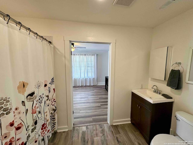 bathroom with wood-type flooring, toilet, vanity, and ceiling fan