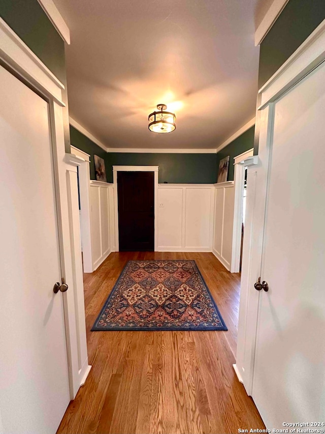 hallway with light hardwood / wood-style flooring and ornamental molding