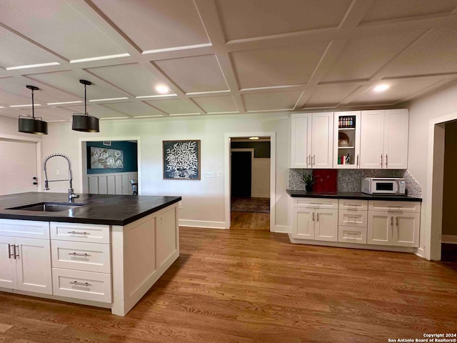 kitchen with light hardwood / wood-style flooring, white cabinets, decorative backsplash, pendant lighting, and sink