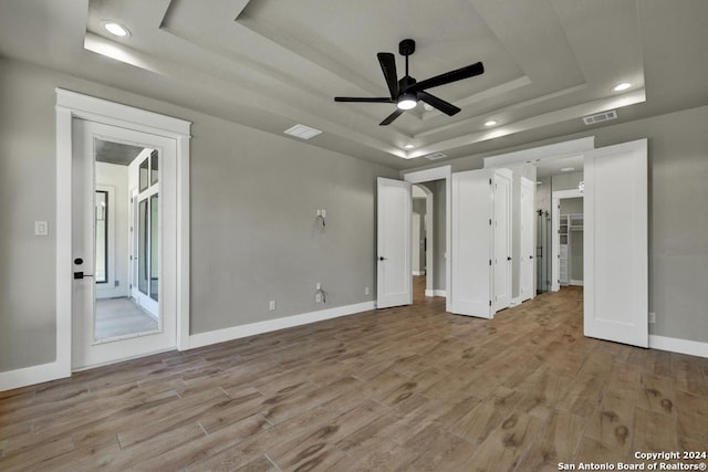 unfurnished bedroom featuring light hardwood / wood-style floors, a raised ceiling, and ceiling fan