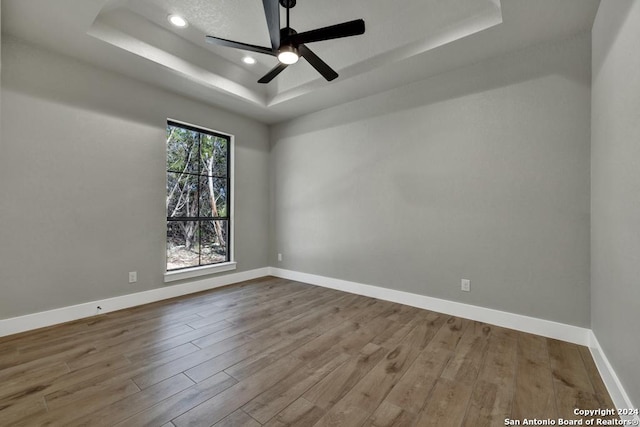 unfurnished room featuring a tray ceiling, ceiling fan, and hardwood / wood-style flooring