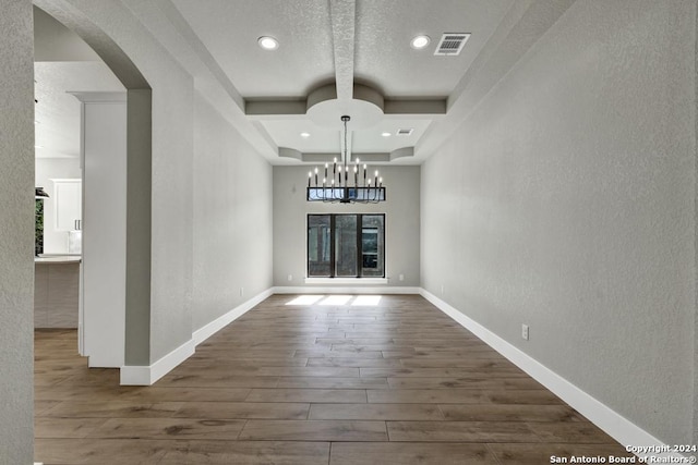 unfurnished dining area featuring coffered ceiling, dark hardwood / wood-style flooring, a chandelier, and beamed ceiling