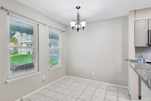 unfurnished dining area featuring an inviting chandelier, light tile patterned floors, and plenty of natural light