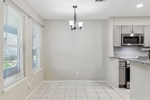 kitchen featuring light tile patterned flooring, a notable chandelier, tasteful backsplash, stainless steel appliances, and gray cabinetry