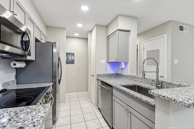 kitchen featuring gray cabinets, decorative backsplash, sink, light stone countertops, and appliances with stainless steel finishes