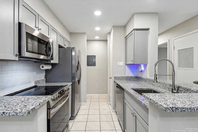 kitchen with light tile patterned floors, backsplash, electric panel, gray cabinets, and stainless steel appliances