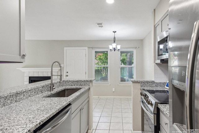 14343 Judson Rd Unit 803, San Antonio, TX 78233 - kitchen with stainless steel appliances, a sink, a chandelier, light tile patterned flooring, and a tiled fireplace