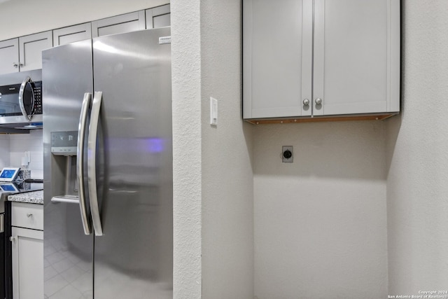 kitchen with gray cabinets, stainless steel appliances, and light stone counters