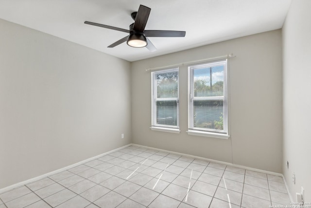 empty room with light tile patterned flooring, ceiling fan, and a healthy amount of sunlight