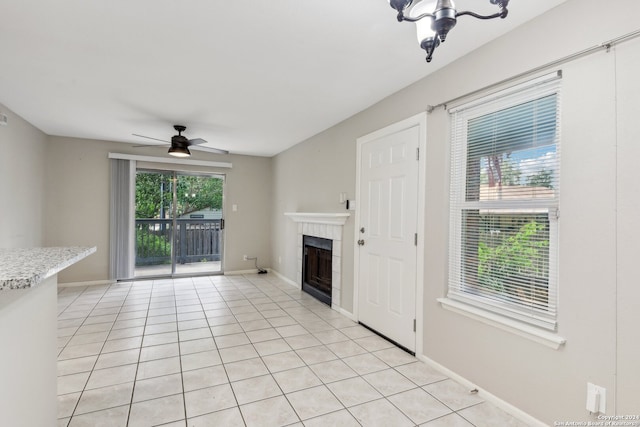 unfurnished living room featuring a fireplace, ceiling fan, and light tile patterned floors