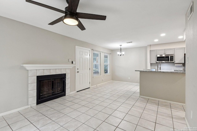 14343 Judson Rd Unit 803, San Antonio, TX 78233 - unfurnished living room with a chandelier, ceiling fan, a tiled fireplace, recessed lighting, and light tile patterned floors