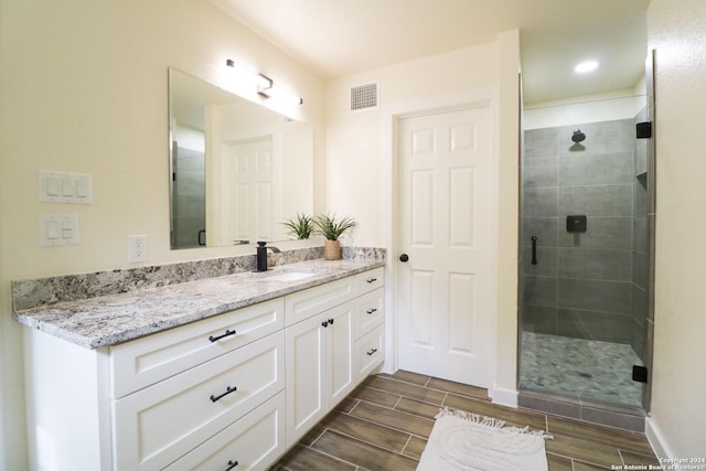 bathroom with a shower with shower door and vanity