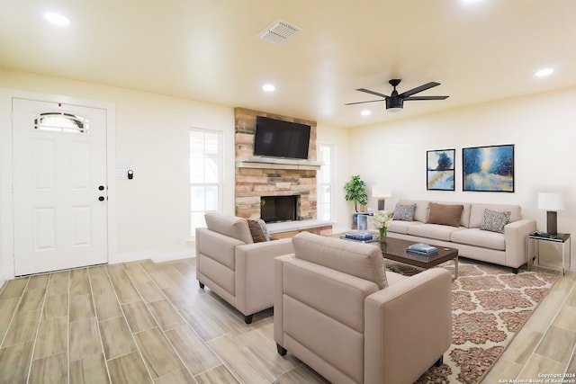 living room with ceiling fan and a stone fireplace