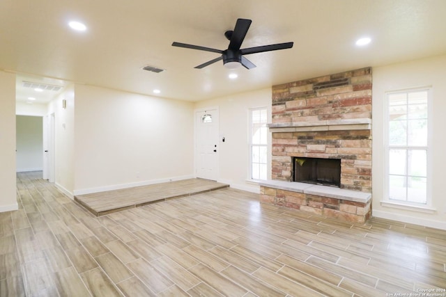 unfurnished living room featuring ceiling fan, a healthy amount of sunlight, and a fireplace