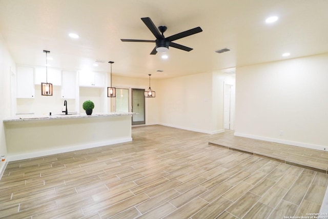 unfurnished living room with ceiling fan and sink