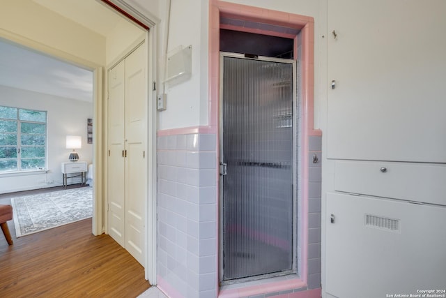 bathroom featuring wood-type flooring and a shower with shower door