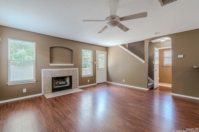 unfurnished living room with ceiling fan, wood-type flooring, and a tile fireplace