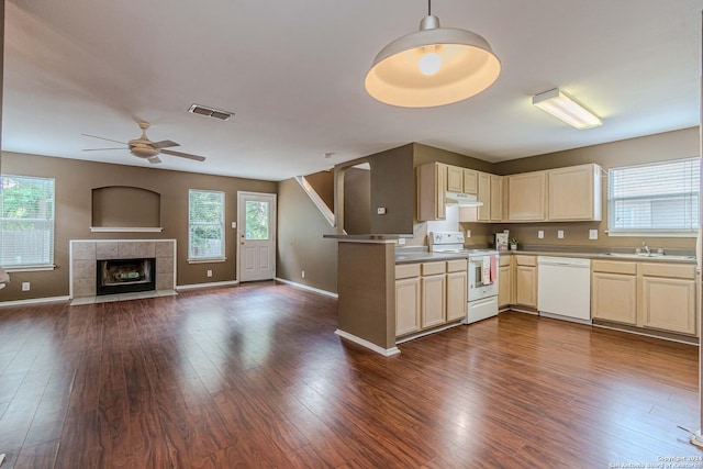 kitchen featuring a healthy amount of sunlight, kitchen peninsula, a tile fireplace, and white appliances