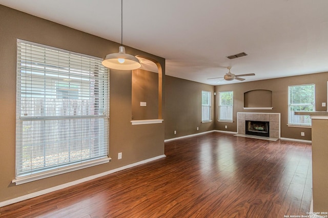 unfurnished living room with ceiling fan, dark wood-type flooring, and a tile fireplace