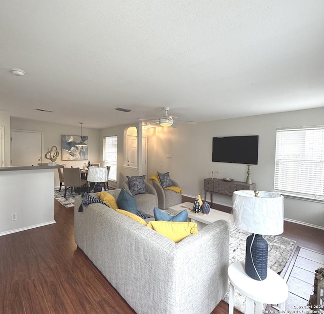 living room featuring ceiling fan and dark wood-type flooring