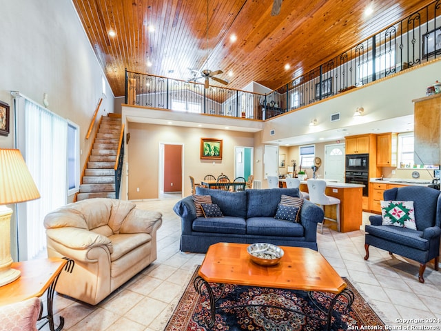 tiled living room featuring ceiling fan, a towering ceiling, and wooden ceiling