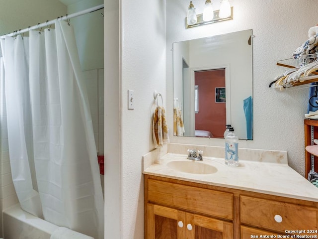 full bath with a textured wall, vanity, and shower / bathtub combination with curtain