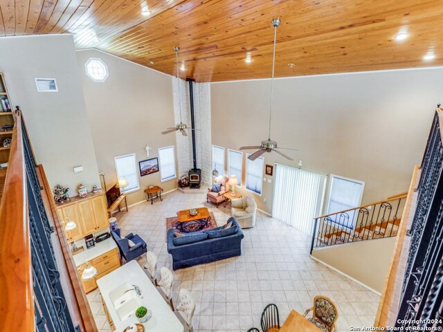 living room featuring ceiling fan, light tile patterned flooring, a high ceiling, and wooden ceiling