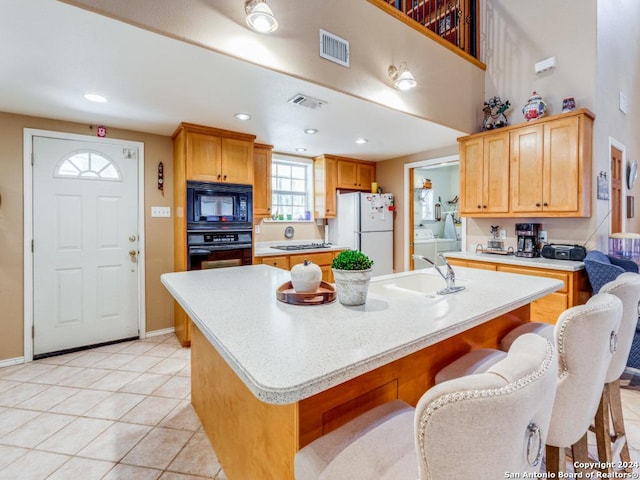 kitchen with visible vents, light countertops, washer and dryer, black appliances, and a sink