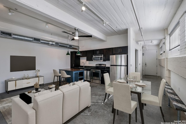 living room with rail lighting, ceiling fan, concrete floors, and beam ceiling