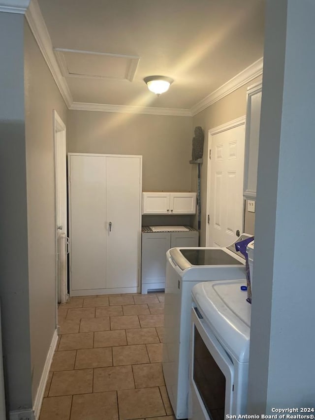 clothes washing area featuring washer and dryer, ornamental molding, and cabinets