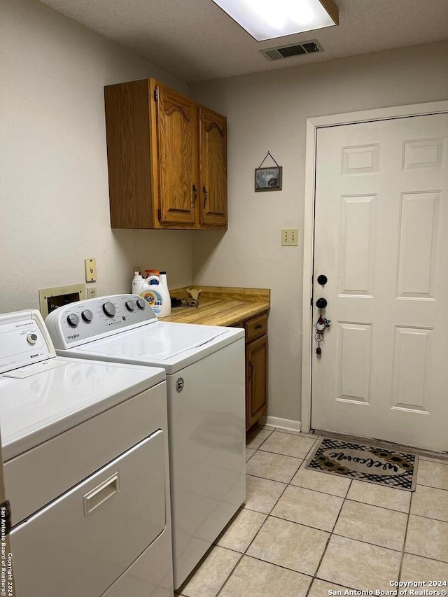 laundry area featuring cabinets, washing machine and clothes dryer, and light tile patterned flooring