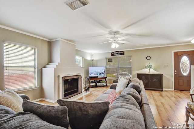 living room featuring light hardwood / wood-style floors, ornamental molding, ceiling fan, and plenty of natural light