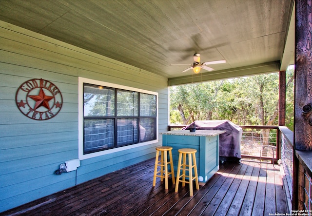 wooden terrace featuring grilling area and ceiling fan