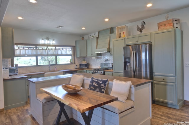 kitchen with custom exhaust hood, sink, dark wood-type flooring, and stainless steel appliances