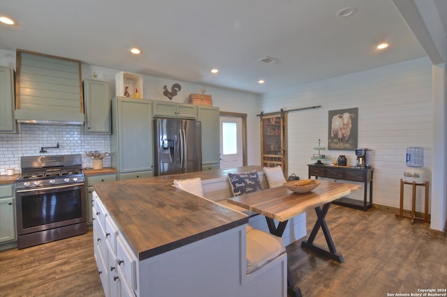 kitchen featuring tasteful backsplash, a barn door, wood counters, stainless steel appliances, and dark wood-type flooring