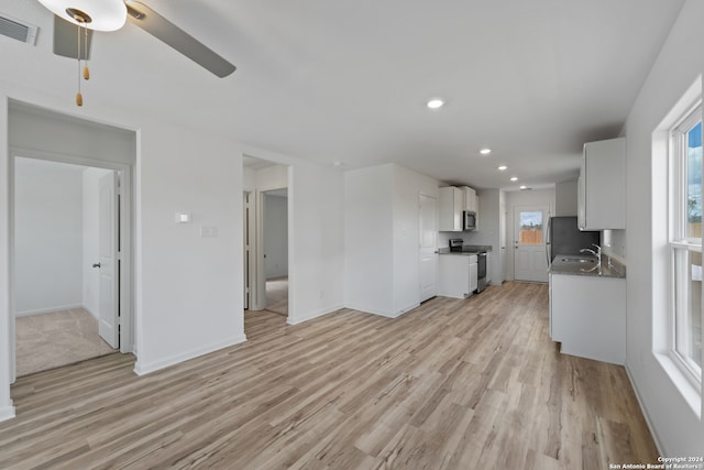 unfurnished living room featuring sink, ceiling fan, light hardwood / wood-style floors, and a wealth of natural light