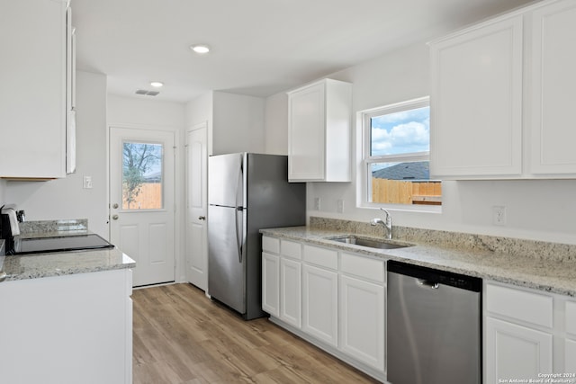 kitchen featuring appliances with stainless steel finishes, light hardwood / wood-style floors, light stone countertops, sink, and white cabinetry