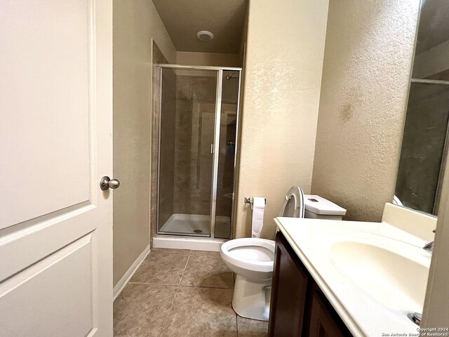 bathroom with tile patterned flooring, a shower with door, toilet, and vanity