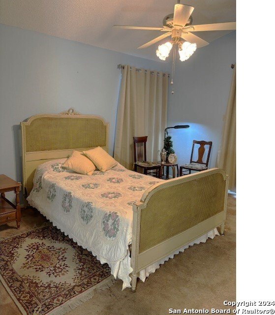 bedroom featuring carpet floors, a textured ceiling, and ceiling fan