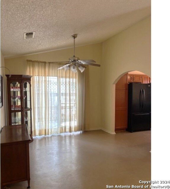 empty room featuring concrete floors, lofted ceiling, a textured ceiling, and ceiling fan