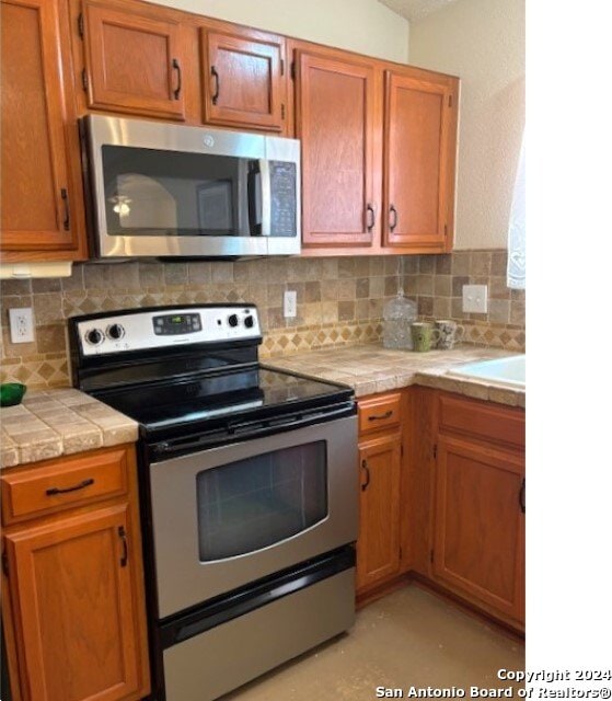 kitchen with backsplash, tile counters, and appliances with stainless steel finishes