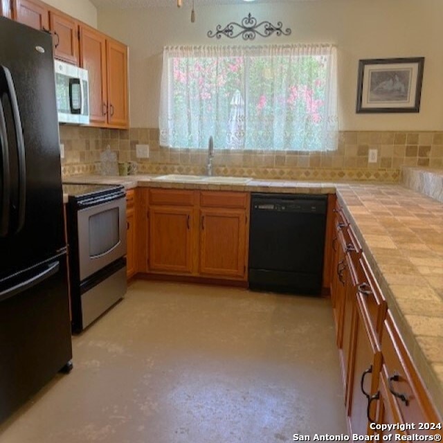 kitchen featuring black appliances, tile countertops, tasteful backsplash, and sink