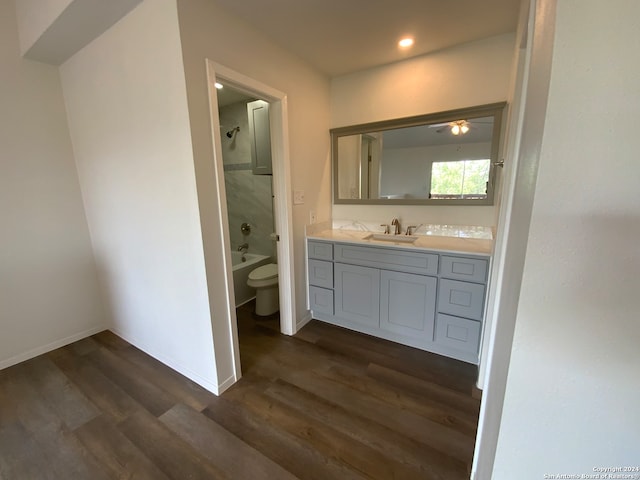 full bathroom with hardwood / wood-style floors, tiled shower / bath, toilet, vanity, and ceiling fan