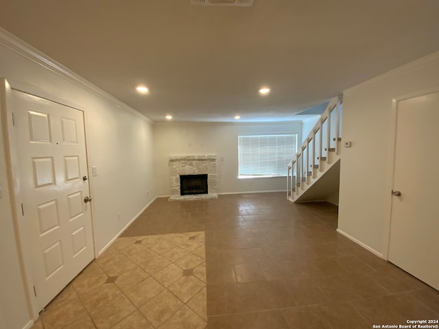 unfurnished living room with tile patterned floors, a stone fireplace, and crown molding