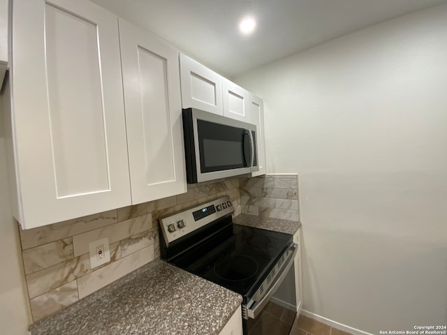 kitchen featuring decorative backsplash, stainless steel appliances, tile patterned floors, and white cabinets